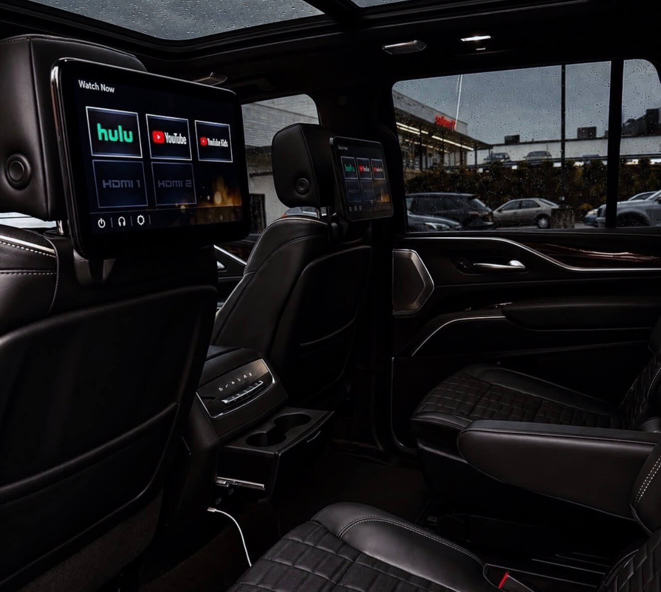 Black leather captain's chairs and rear-seat entertainment screens in a chauffeured Cadillac Escalade Platinum